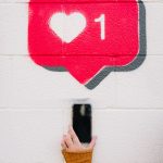 A person taking a photo of the drawing of an Instagram like feature on a wall