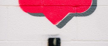 A person taking a photo of the drawing of an Instagram like feature on a wall