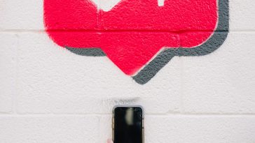 A person taking a photo of the drawing of an Instagram like feature on a wall