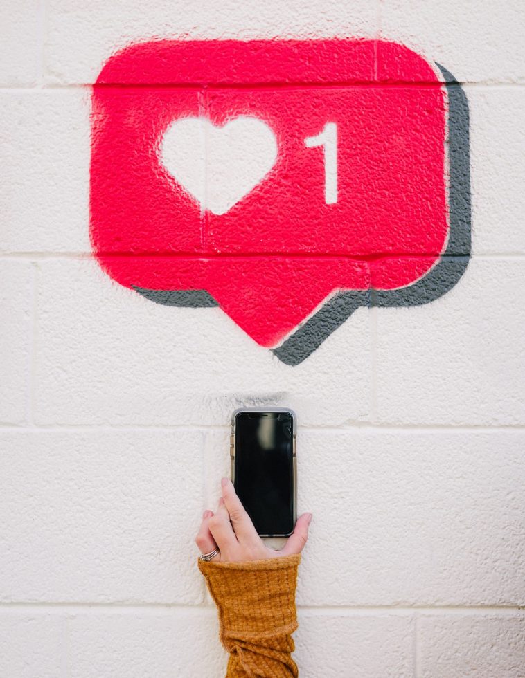 A person taking a photo of the drawing of an Instagram like feature on a wall