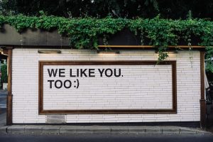 A sign on a while-tile wall with a quote "we like you too:)"